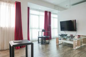 a living room with a television and red curtains at Cozy Living 1BR at Pakubuwono Terrace Apartment By Travelio in Jakarta