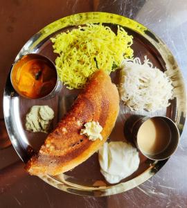 um prato de alimentos com arroz e legumes sobre uma mesa em Hanakodu homestay em Sringeri