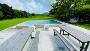 a swimming pool with two benches and a picnic table at Butterfly B&B in Manzhou