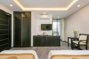 a hotel room with two beds and a tv at Hanami Hotel Danang in Da Nang