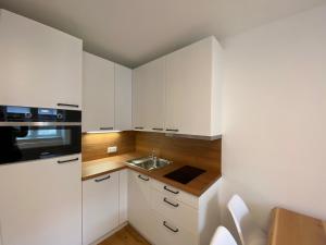 a kitchen with white cabinets and a sink at Apartments Freitag - H1 in Winden am See