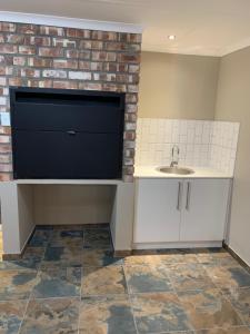 a bathroom with a sink and a brick wall at Oasis Self-Catering in Swakopmund