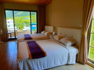 two beds in a room with a large window at Two Fish Homestay in Lanyu