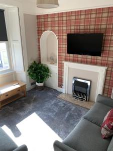 a living room with a fireplace with a flat screen tv at The Teviot in the centre of Melrose in Melrose