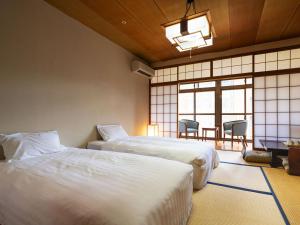 a bedroom with two beds and a table and chairs at Hotel Flags Isahaya Nagasaki in Isahaya