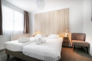 a hotel room with a large bed and a chair at Hôtel La Petite Sirène Quiberon in Quiberon