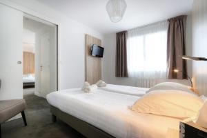 a bedroom with a large white bed and a window at Hôtel La Petite Sirène Quiberon in Quiberon