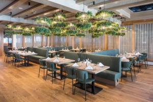 a dining room with tables and chairs and chandeliers at Falkensteiner Family Hotel Sonnenalpe in Sonnenalpe Nassfeld