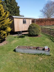 a garden with a table and a bench in the grass at Lucker mill shepherds huts in Lucker