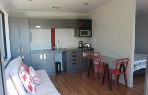eine Küche mit einem Sofa und einem Tisch in einem Zimmer in der Unterkunft Poppy Apartment in Coromandel Town