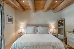 Un dormitorio con una cama grande con sábanas blancas y techos de madera. en Domaine Les Roullets, en Oppède