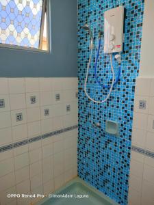 uma casa de banho com um chuveiro com azulejos azuis em imanAdam Laguna Apartment em Porto Dickson