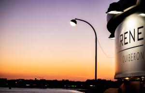 a street light and a sign with the sunset in the background at Hôtel La Petite Sirène Quiberon in Quiberon
