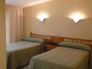 Schlafzimmer mit 2 Betten und Wandbeleuchtung in der Unterkunft Hotel Agarimo playa Areas in Areas