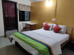 a bedroom with a large bed with red and green pillows at Abhimaan Residency in Gulbarga