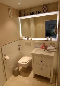 ein Badezimmer mit Toilette, Waschbecken und Spiegel in der Unterkunft Arielle in Westerland