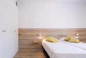 two beds in a room with white walls and wooden floors at Apartaments La Rosella in Roses