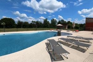 una piscina con 2 tumbonas junto a ella en Le Village de Cottages - Le Pôle du Cheval et de l'Âne en Lignières