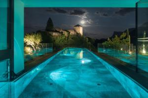 a swimming pool at night with a castle in the background at Der Waldhof in Vollan
