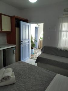 a room with two beds and a kitchen and a door at Amorgaia 1 in Katapola
