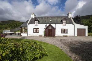 a large white house with a large garage at Rowan Cottage in Aviemore