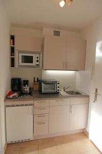 a small kitchen with white cabinets and a microwave at Nina in Wenningstedt