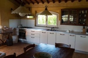 a kitchen with white cabinets and a wooden table at La Casa delle Rose in Terranuova Bracciolini