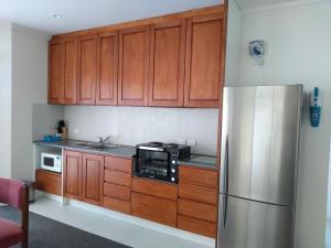 a kitchen with wooden cabinets and a stainless steel refrigerator at Quiet location with view and public transport in Wellington +5 photos