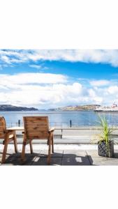 two wooden benches sitting next to a body of water at MacKays in Oban