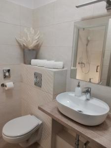 a white bathroom with a sink and a toilet at Alfa Hotel in Győr