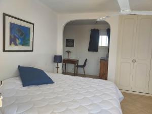 a bedroom with a large white bed and a desk at Villa Le Sud in Les Issambres
