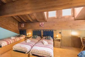 two beds in a room with wooden walls and windows at Nadir - Casa Azzurra in Livigno