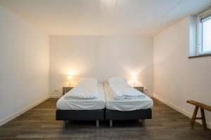 twee bedden in een kamer met twee lampen aan de muur bij Hoogelandt 106F in De Koog