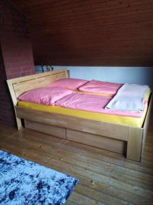 uma cama de madeira com lençóis cor-de-rosa num piso de madeira em Ferienhaus Ullrich em Augustusburg