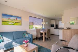 a living room with a blue couch and a kitchen at Hoogelandt 92 in De Koog