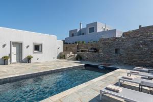 a swimming pool with chairs and a building at Nevermind vacations villaB in Kastrianí