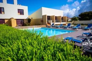 a swimming pool with lounge chairs and a building at Hotel Apartamento Porto Covo in Porto Covo