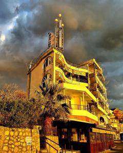 een geel gebouw met een palmboom ervoor bij Malibu Apartments in Sutomore