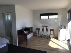 a room with a bed and a kitchen with a table and stool at Stylish Space in Twizel