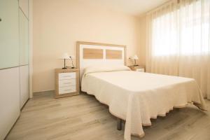 a white bedroom with a bed and a window at APCOSTAS Los Iris - familiar in Playa de Gandia +28 photos