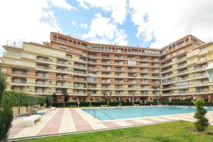a large building with a swimming pool in front of it at APCOSTAS Los Iris - familiar in Playa de Gandia