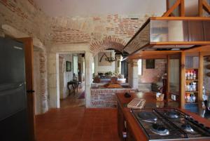 a kitchen with a stove and a living room at Le Manoir du Port in Grézels