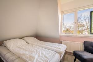 a bed in a room with a window and a chair at Nieuwlanderweg 65 in De Waal