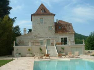 a house with a swimming pool in front of a building at Le Manoir du Port in Grézels