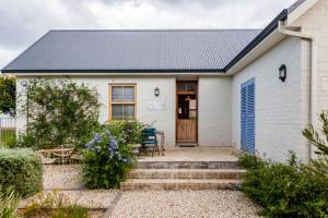 a white house with a blue door and a patio at Nerf-af Cottage and private ROOMs at Onrus , Hermanus in Hermanus