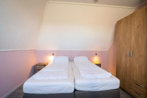two beds in a small room with two lights at Nieuwlanderweg 69 in De Waal