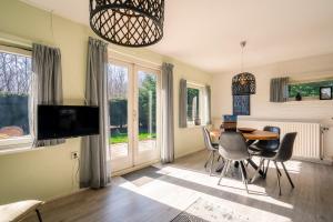 a living room with a table and chairs and a television at Nieuwlanderweg 69 in De Waal