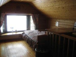 1 dormitorio con 1 cama en una habitación con ventana en Aarnitupa, cottage by lake Kylmäluoma, 