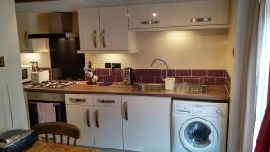 a kitchen with a sink and a washing machine at Clover Cottage in Winster
