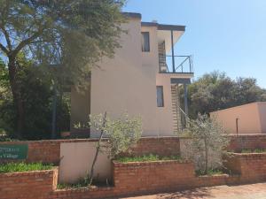 a house behind a brick wall with trees in front of it at Vaal de Grace River Village in Parys